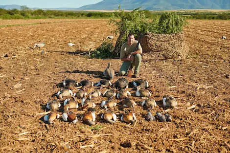 A hunter posing with the Ducks and geese he shot on a successful geese hunting trip