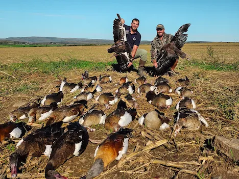 Two hunters proudly posing with their duck and geese they shot after another successfull hunting expedition